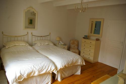 a bedroom with a large white bed and a dresser at L'Ancienne Forge 27 rue de la Crèche Bourg Born in Villeréal