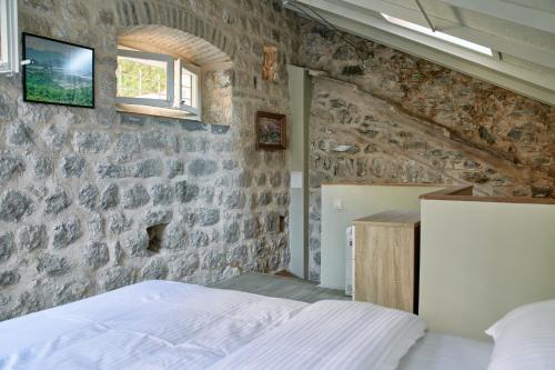 a bedroom with a stone wall and a bed at Waterfront Historical Villa Perast in Perast