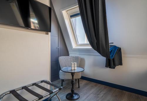 a small table and chair in a room with a window at Hotel Mademoiselle in Paris