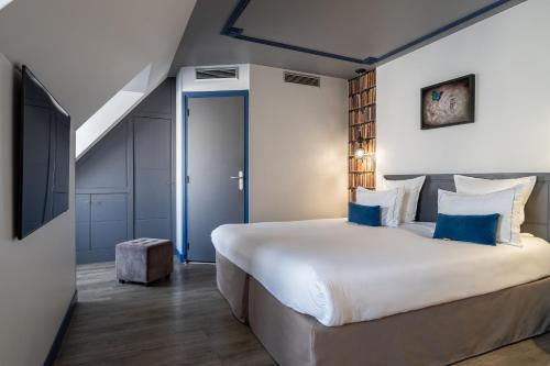 a bedroom with a large white bed with blue accents at Hotel Mademoiselle in Paris