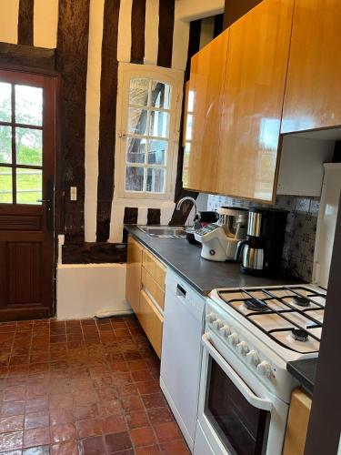 Il comprend une cuisine équipée d'une cuisinière. four supérieur à côté d'une fenêtre dans l'établissement Chaumière normande, les pommiers proches de la mer, à Blonville-sur-Mer