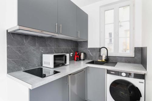 une cuisine avec un lave-linge et un micro-ondes dans l'établissement Appartement service Studio au Coeur du 19e - 2P, à Paris