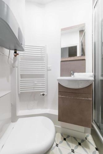 une salle de bain blanche avec un lavabo et des toilettes dans l'établissement Appartement service Studio au Coeur du 19e - 2P, à Paris