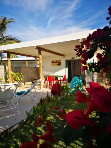 a house with a patio with red flowers in the yard at Pousada Recanto Beija-Flor in Fortim