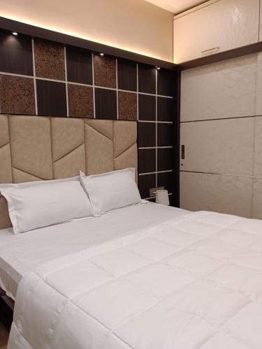 a bedroom with a large white bed and a door at Satya Stays Premium Boutique Apartment in Navi Mumbai