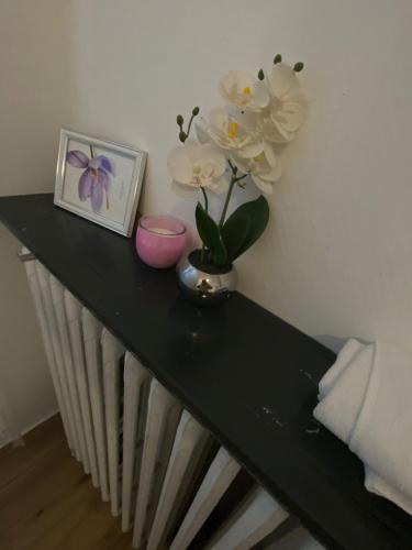 a black table with a picture and flowers on it at Hôtel & Restaurant ISVARA in Breteuil