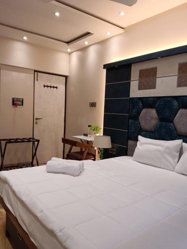 a bedroom with a large white bed and a table at Satya Stays Premium Boutique Apartment in Navi Mumbai