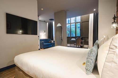 a hotel room with a large white bed and a tv at Hotel Mademoiselle in Paris