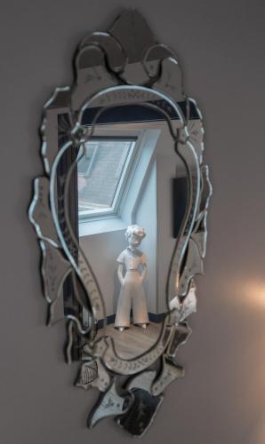 a mirror hanging on a wall with a statue in it at Hotel Mademoiselle in Paris