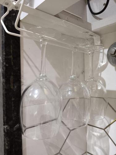 three wine glasses sitting on top of a shelf at Satya Stays Premium Boutique Apartment in Navi Mumbai