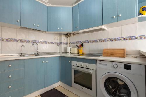 a kitchen with blue cabinets and a washing machine at Bungalow en Gran Alacant con Terraza y piscina comunitaria in Puerto Marino