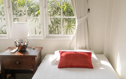 a bedroom with a bed with a red pillow and a window at 10mins to BKK airport 3BR Group Stay in Bangkok