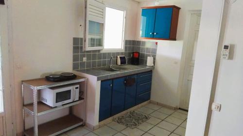 a small kitchen with blue cabinets and a microwave at Villa Belle Horizon in La Trinité