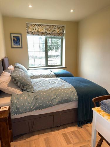 a bedroom with a large bed with a window at Dorset Stay, Coast & Countryside in Puncknowle
