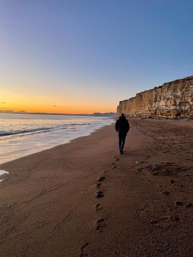 a man walking on the beach with footprints in the sand at Dorset Stay, Coast & Countryside in Puncknowle
