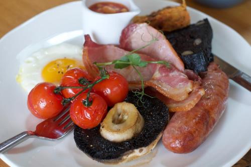 a plate of breakfast food with eggs sausage and tomatoes at Hazel Hobbit Pod at Cowbridge Cabins in Cowbridge