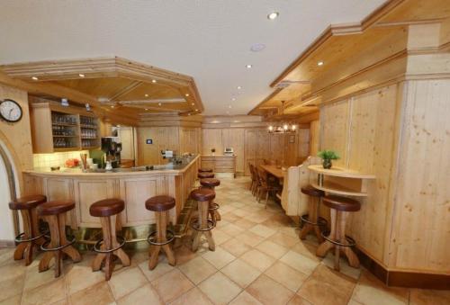 a kitchen with a bar with stools and a table at Hotel Sailer in Sankt Anton am Arlberg
