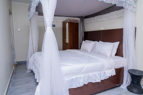 a bedroom with a canopy bed with white curtains at Stadium View Executive Guest House in Lilongwe