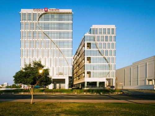 two tall buildings with a tree in front of a street at Studio M Muscat in Muscat