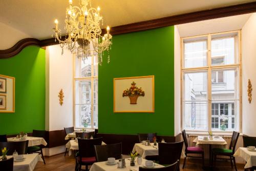 a dining room with green walls and tables and a chandelier at Pertschy Palais Hotel in Vienna