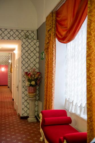 a living room with a red chair and a window at Pertschy Palais Hotel in Vienna