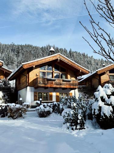 a large wooden house with a balcony in the snow at AlpenPura - Chalet mit Sauna und Panoramablick in Neukirchen am Großvenediger