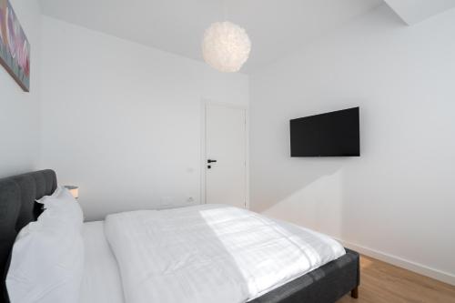 a white bedroom with a bed and a flat screen tv at AeroPrime - LOFT in Tunari
