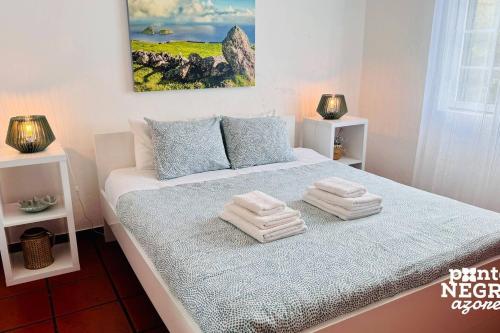 a bedroom with a bed with towels on it at Casa da Maresia by PontaNegraAzores in Biscoitos