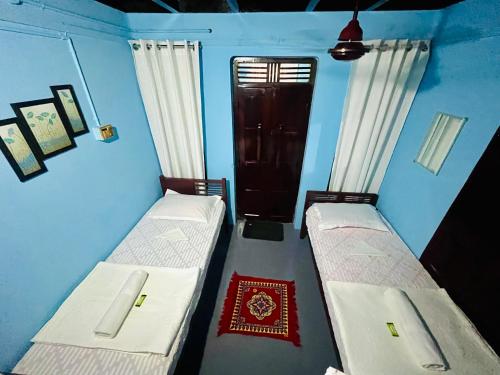 two beds in a room with blue walls and a door at Arapura Veedu Heritage Homestay in Kizhillam