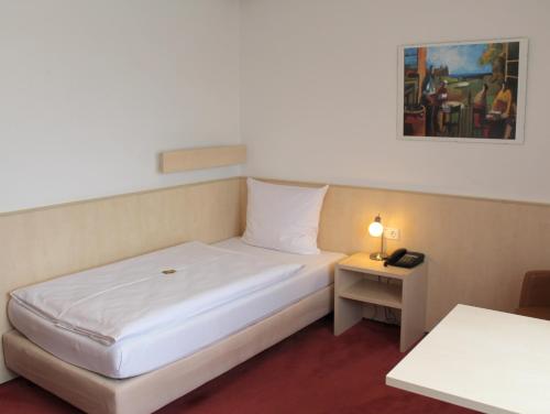 a hotel room with a bed and a night stand with a lamp at Hotel am Bad in Esslingen