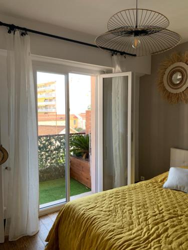 - une chambre avec un lit et une grande porte coulissante en verre dans l'établissement Le Magilena T2, à Cannes