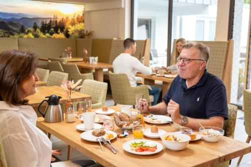 a man and woman sitting at a table in a restaurant at Wellnesshotel Sonnenhof & Sonnhalde in Ühlingen-Birkendorf