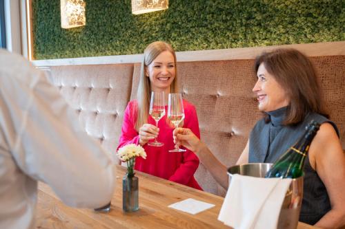 two women sitting at a table with glasses of wine at Wellnesshotel Sonnenhof & Sonnhalde in Ühlingen-Birkendorf