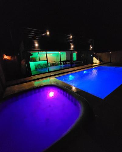 a swimming pool at night with purple and green lights at Beach house with heated pool and jacuzzi in Villa Argentina