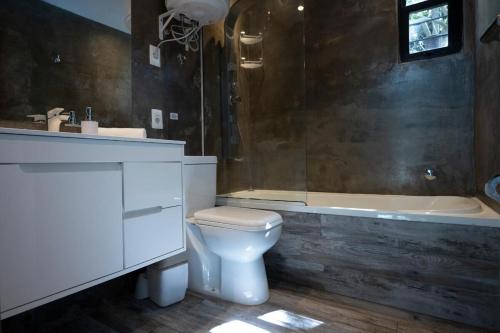 a bathroom with a white toilet and a bath tub at Beach house with heated pool and jacuzzi in Villa Argentina