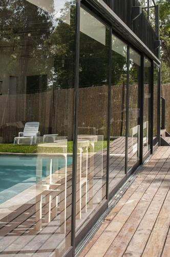 a glass house with chairs and a swimming pool at Beach house with heated pool and jacuzzi in Villa Argentina
