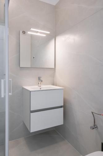 a white bathroom with a sink and a mirror at AeroPrime - LOFT in Tunari