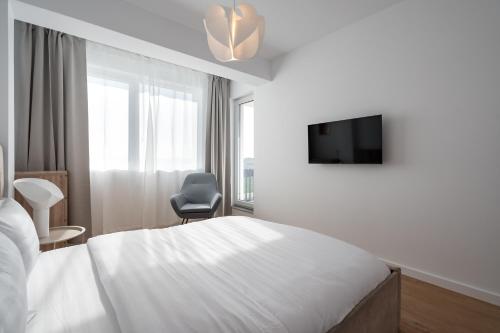 a bedroom with a bed and a tv and a chair at AeroPrime - LOFT in Tunari