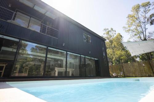 a house with glass windows and a swimming pool at Beach house with heated pool and jacuzzi in Villa Argentina