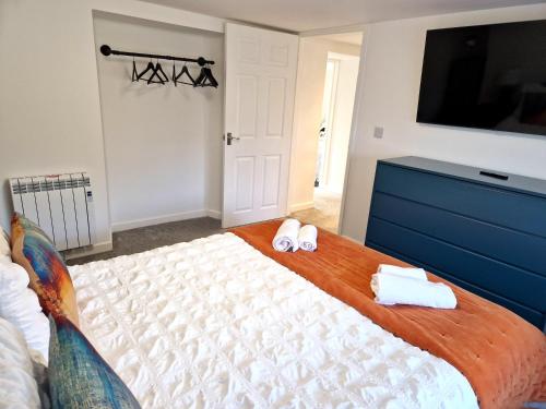 a bedroom with a bed with towels and a tv at Very Spacious, Great location. Castle and Sea view in Marazion