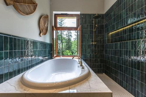 HeřmaniceChâteau du Golf next to Malevil Golf Resort的浴室铺有绿色瓷砖,配有浴缸。