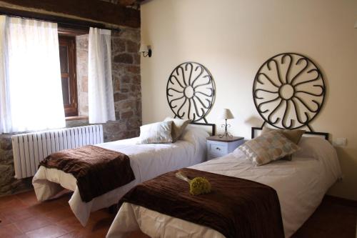 a bedroom with two beds and two mirrors on the wall at Posada Rural La Piñorra in Vinuesa
