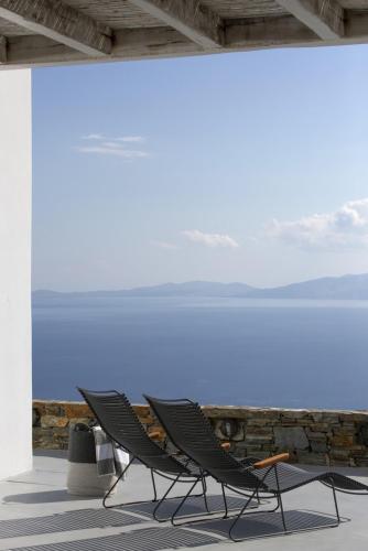 a pair of chairs sitting in front of a wall at House G in Kardiani Tinos in Kardiani