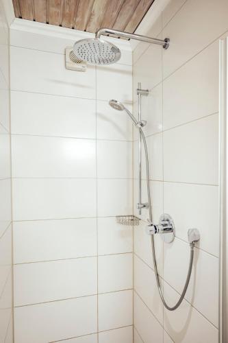 a shower in a bathroom with white tiles at Ferienwohnung Stadtplatz 25 in Traunstein