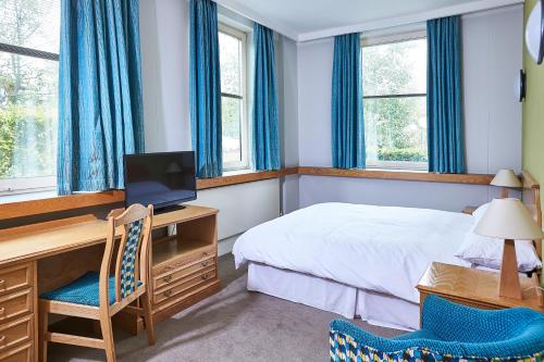 a bedroom with a bed and a desk with a computer at Kents Hill Park Training & Conference Centre in Milton Keynes