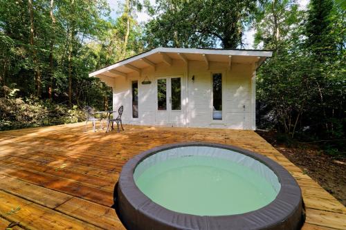 une maison avec un bain à remous sur une terrasse en bois dans l'établissement Le Cottage de St Aubierge, à Mauperthuis