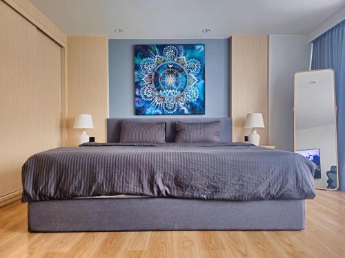 a bedroom with a large bed with a painting on the wall at Wonderful View Duplex in La Vita in Rawai Beach
