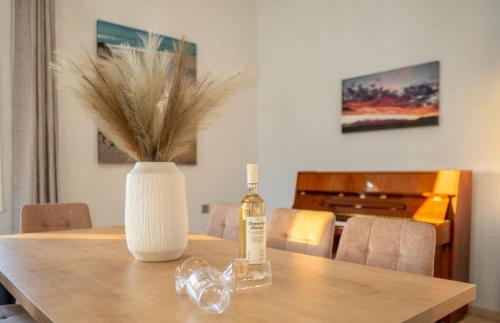 a bottle of alcohol on a wooden table with a vase at Villa Helyra in Heraklio Town