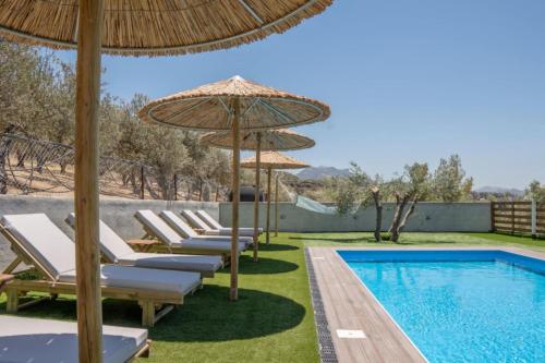 a pool with lounge chairs and umbrellas next to a swimming pool at Villa Helyra in Heraklio Town