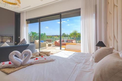 a bedroom with a large white bed with two towels at Villa Elysée - Piscine et jardin Privée Sans vis-à-vis Wifi HD in Sraghna